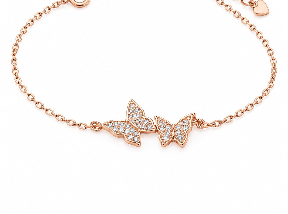 Roségoldenes Armband mit drei Schmetterlingen und funkelnden Steinen auf weißem Hintergrund