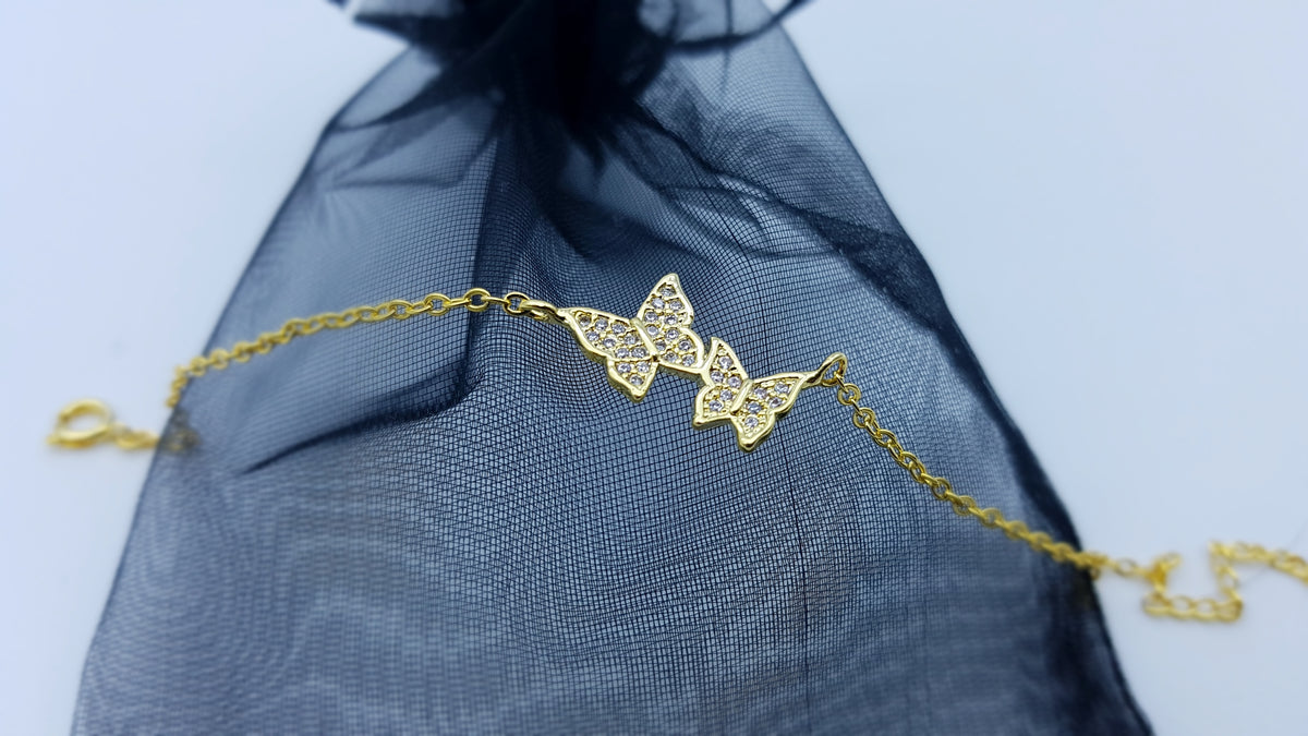 Goldfarbenes Schmetterling Armband für Damen auf dunklem Stoff